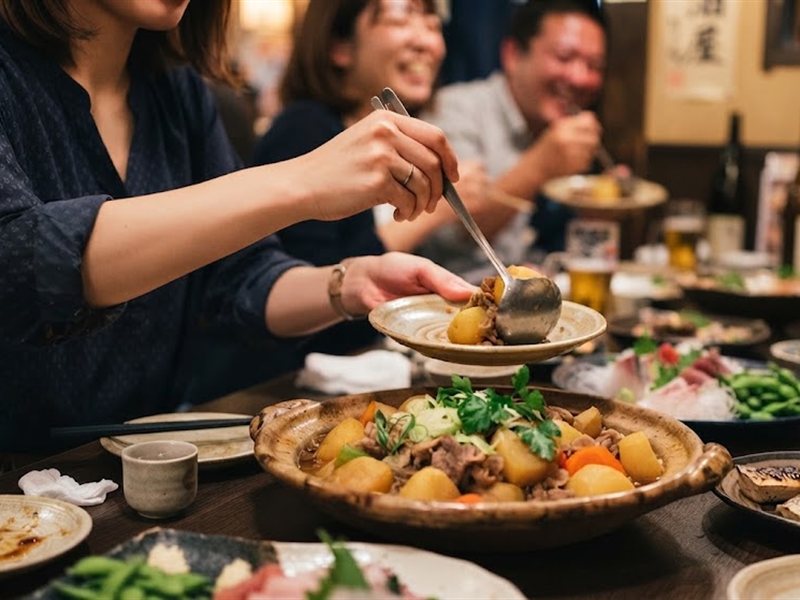 大鉢の煮物を、取り箸で小皿に取り分けているところ